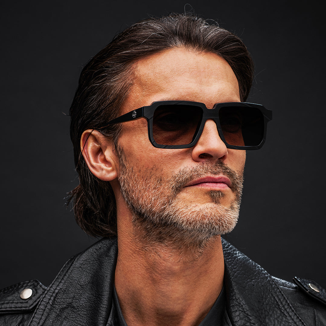 Man wearing black Vinylize Rammstein sunglasses and a black leather jacket against a dark background