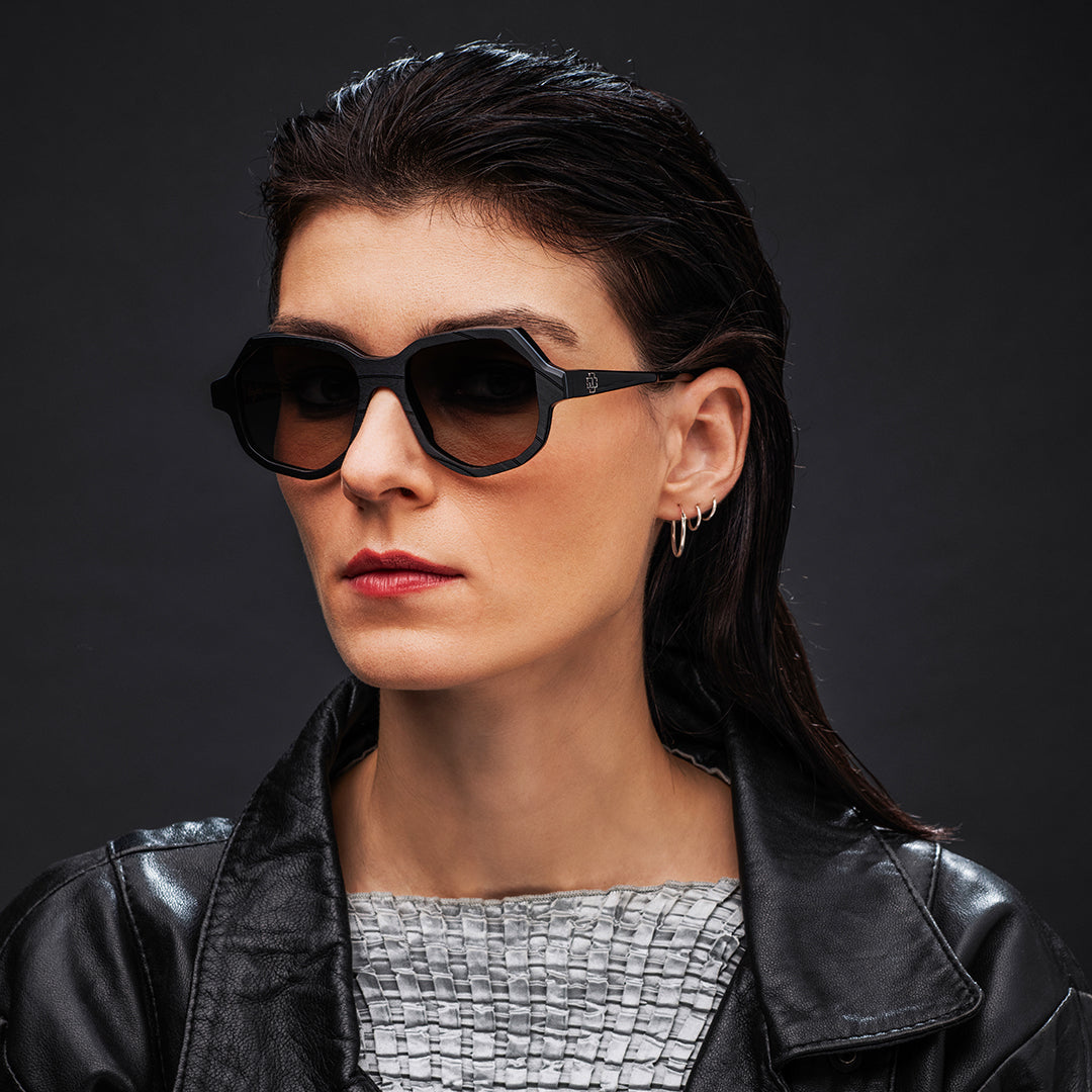 Woman wearing Vinylize Rammstein sunglasses and a black leather jacket against a dark background